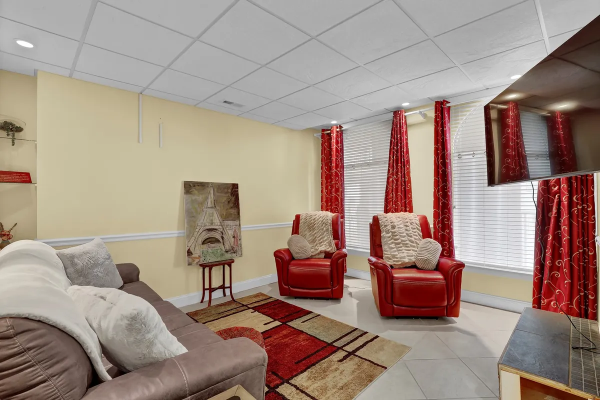 Featuring red recliners, artwork, a sofa, and curtains, this cozy living space radiates comfort and togetherness. The arrangement encourages relaxation, socializing, and group activities.