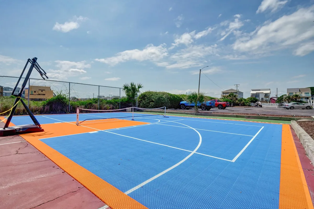 An outdoor sports area featuring a basketball court, tennis net, and lush greenery, inviting guests to step outside, get active, and recharge between work sessions.
