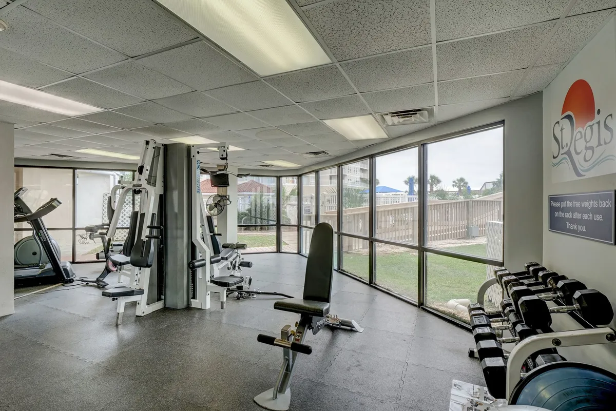 A bright, modern fitness center equipped with gym equipment, large windows letting in natural light, and space for both solo and group workouts. The energetic vibe encourages guests to stay active during their stay.