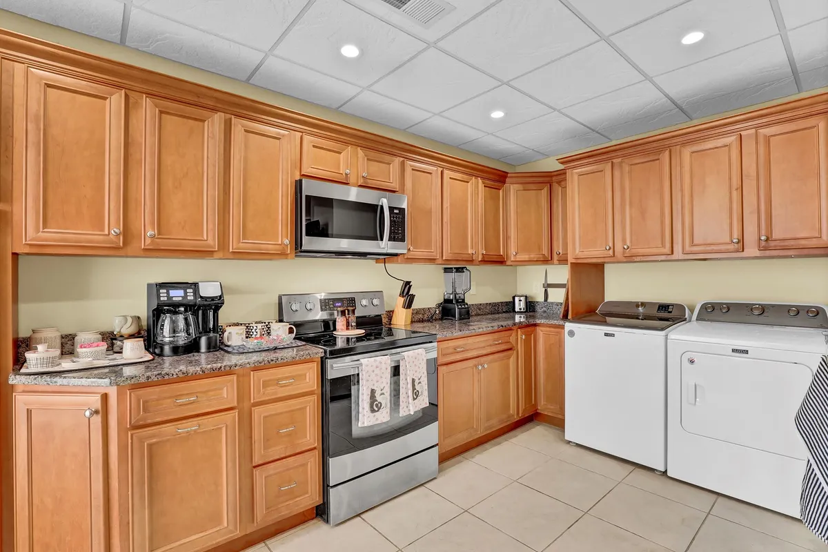 This image displays a modern kitchen with stainless steel appliances, ample cabinetry, a granite countertop, a dedicated coffee station, and even a washer and dryer in view. The space is organized and inviting, perfect for cooking, socializing, or enjoying a morning coffee.