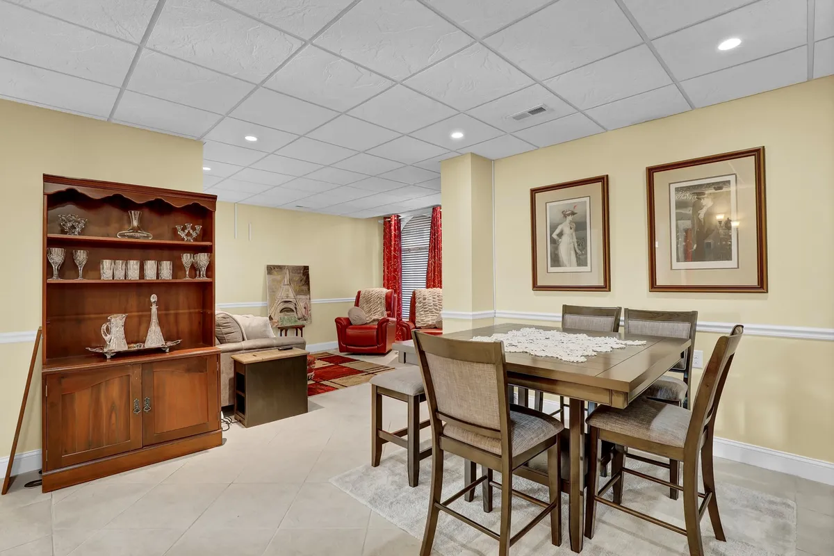 An inviting dining area with a dining table, red armchairs, a decorative cabinet, and framed artwork. The setting is warm and comfortable, ideal for group meals, game nights, or intimate dinners.